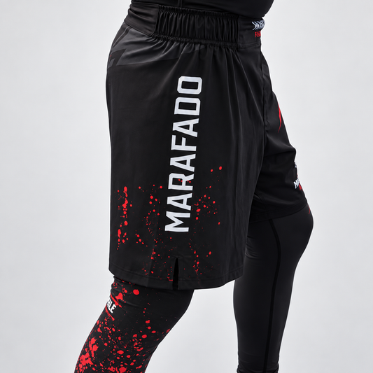 Calções Hard to Handle pretos e vermelhos da Marafado Fightwear, vestidos sobre leggings por modelo masculino, vista lateral com inscrição Marafado.