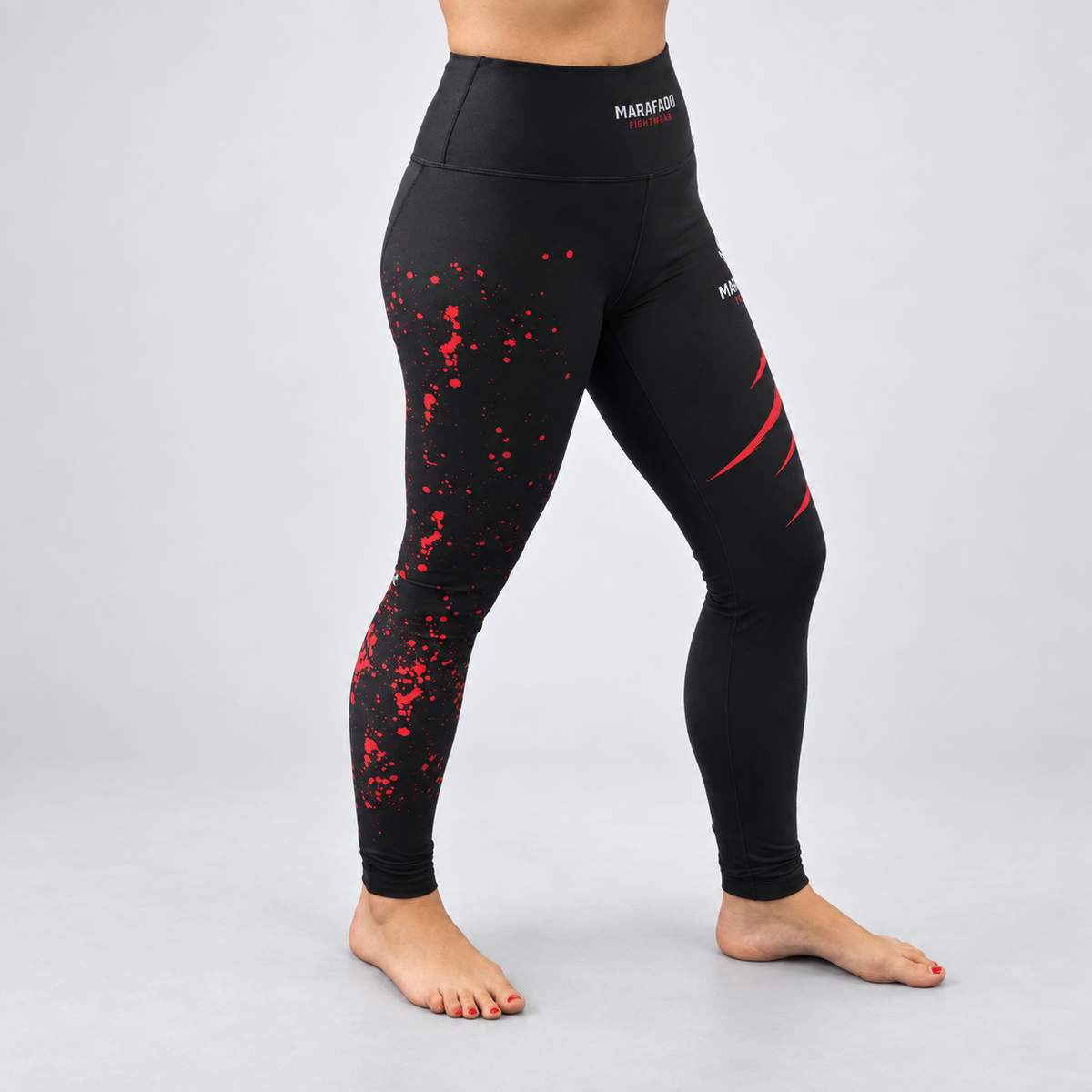 Leggings Hard to Handle pretas e vermelhas da Marafado Fightwear, vestidas por modelo feminino, vista frontal em três quartos com padrão vermelho na perna direita.