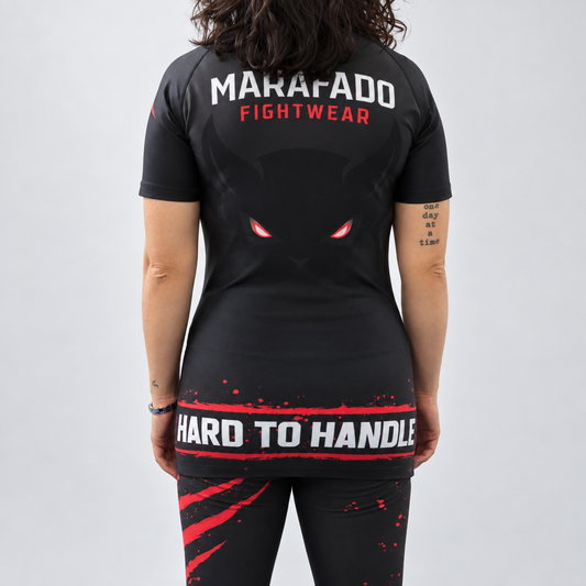 Rashguard Hard to Handle de mulher, de manga curta, preta e vermelha, vestida por modelo, vista de costas com logótipo Marafado e inscrição Hard to Handle.