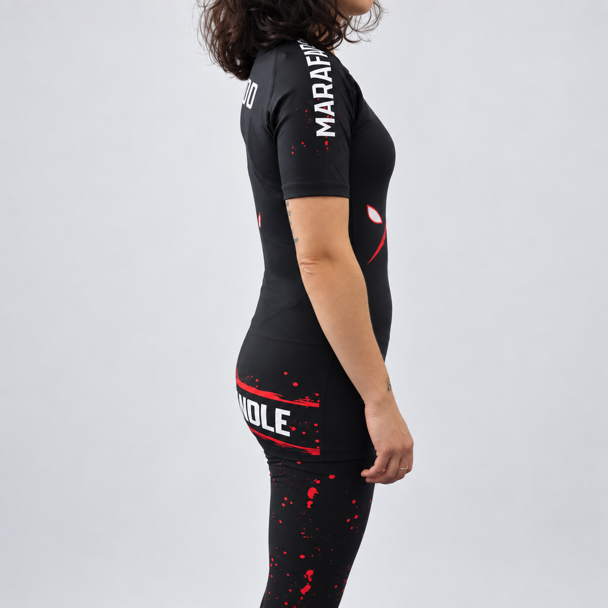 Rashguard Hard to Handle de mulher, de manga curta, preta e vermelha, vestida por modelo, vista lateral direita com inscrição Marafado na manga.