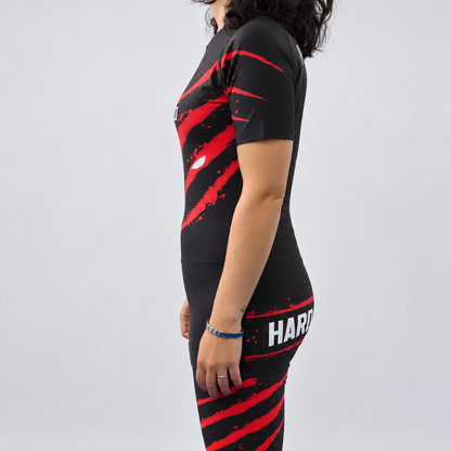 Rashguard Hard to Handle de mulher, de manga curta, preta e vermelha, vestida por modelo, vista lateral esquerda com detalhes vermelhos na manga.